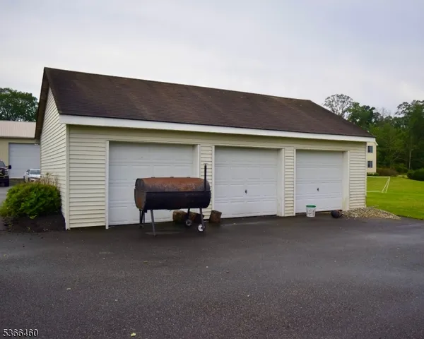 a backyard of a house with barbeque oven and a table under an umbrella
