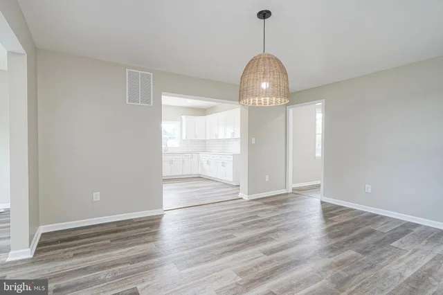 a view of empty room with wooden floor and window