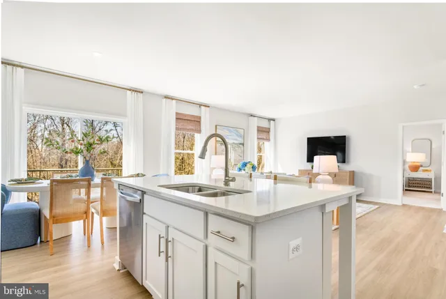 a kitchen with stainless steel appliances granite countertop a stove a sink dishwasher and white cabinets with wooden floor