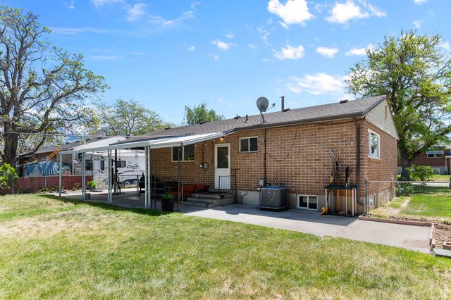 9902 South Poppy Lane Sandy, UT 84094 - Photo 22 of 25 Rear brick facade featuring a covered patio, established lawn, and additional paved area