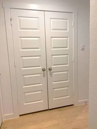 an empty room with kitchen view and a ceiling fan