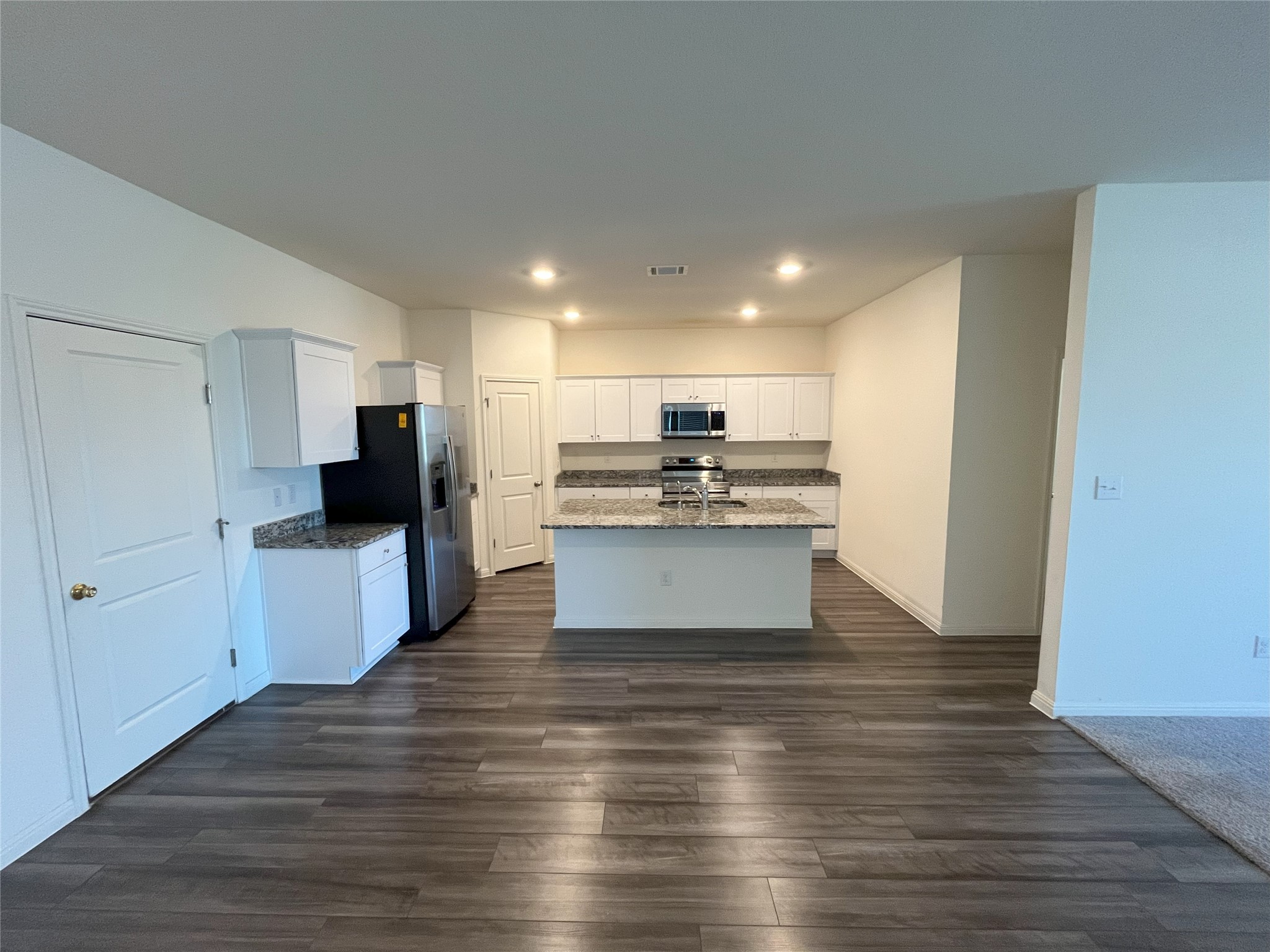215 Light Timber Road Maxwell, TX 78656 - Photo 4 of 33 Gleaming wood-look flooring stretches toward a modern island kitchen with recessed lighting.