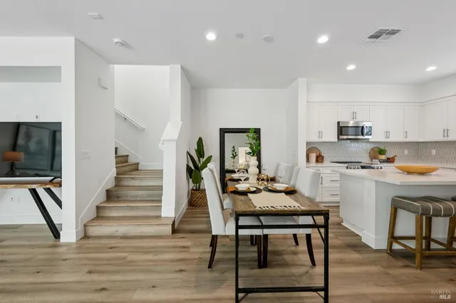 a kitchen with stainless steel appliances kitchen island granite countertop a table chairs sink and cabinets