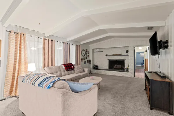 a view of a kitchen with kitchen island a large window cabinets a sink and stainless steel appliances