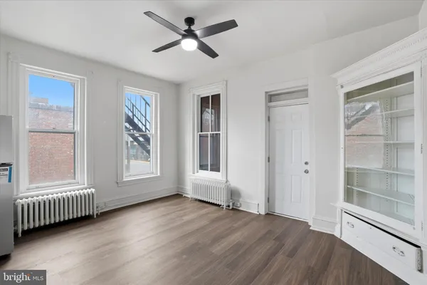 a view of an empty room with a window and wooden floor