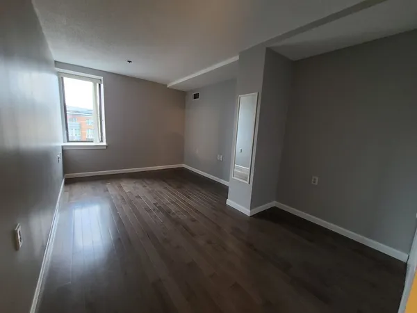 an empty room with wooden floor and windows