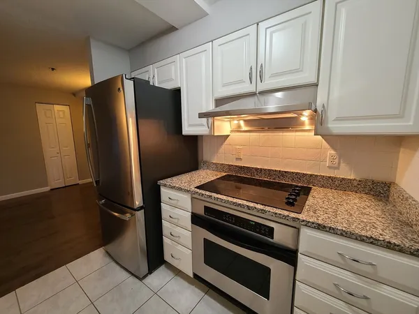 a kitchen with granite countertop a refrigerator stove and cabinets