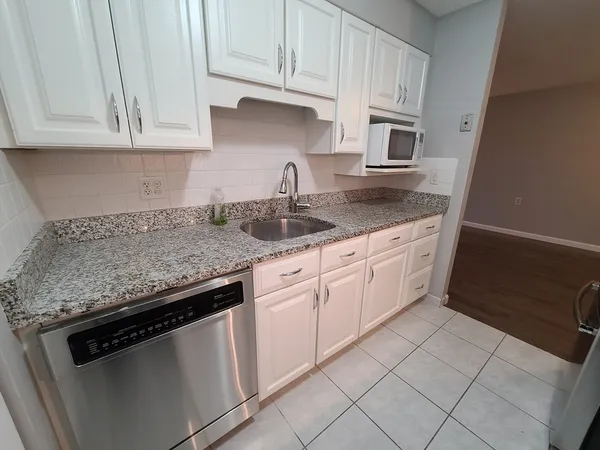 a kitchen with granite countertop white cabinets and a sink