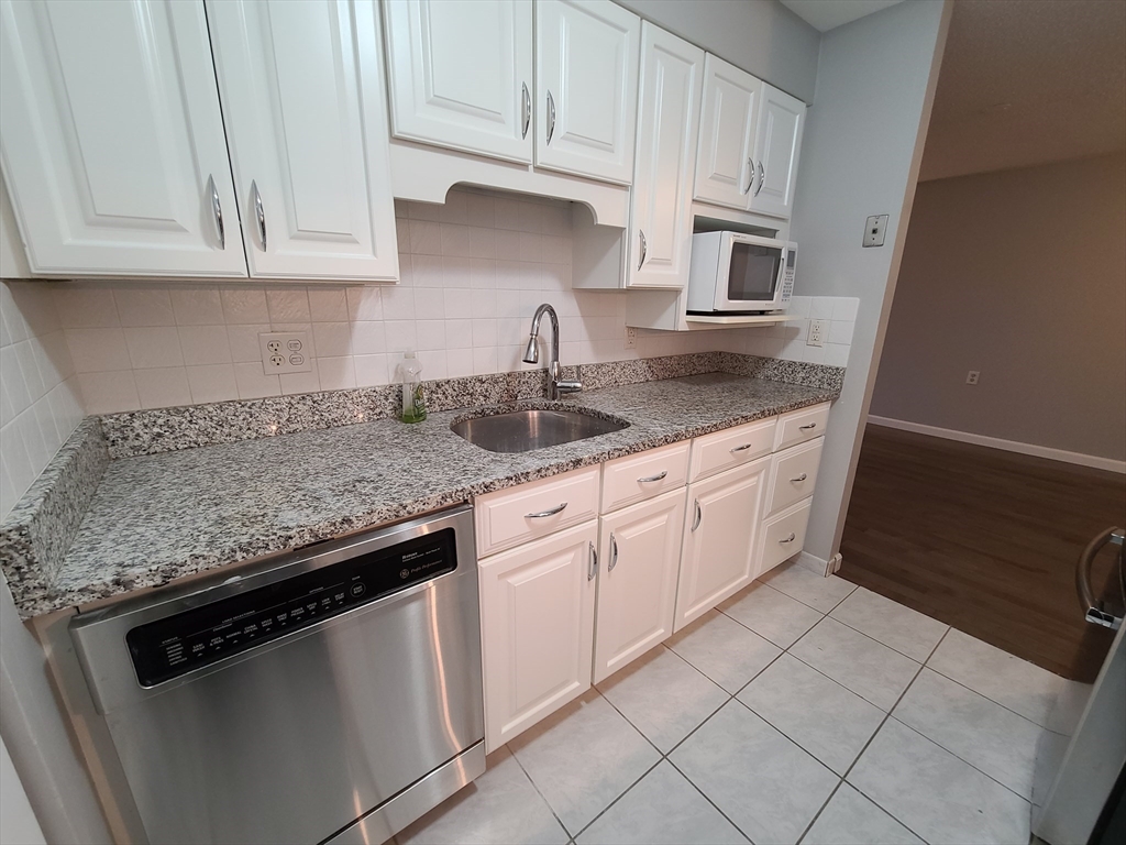 357 Commercial Street, Unit 507 Boston, MA 02109 - Photo 5 of 22 a kitchen with granite countertop white cabinets and a sink