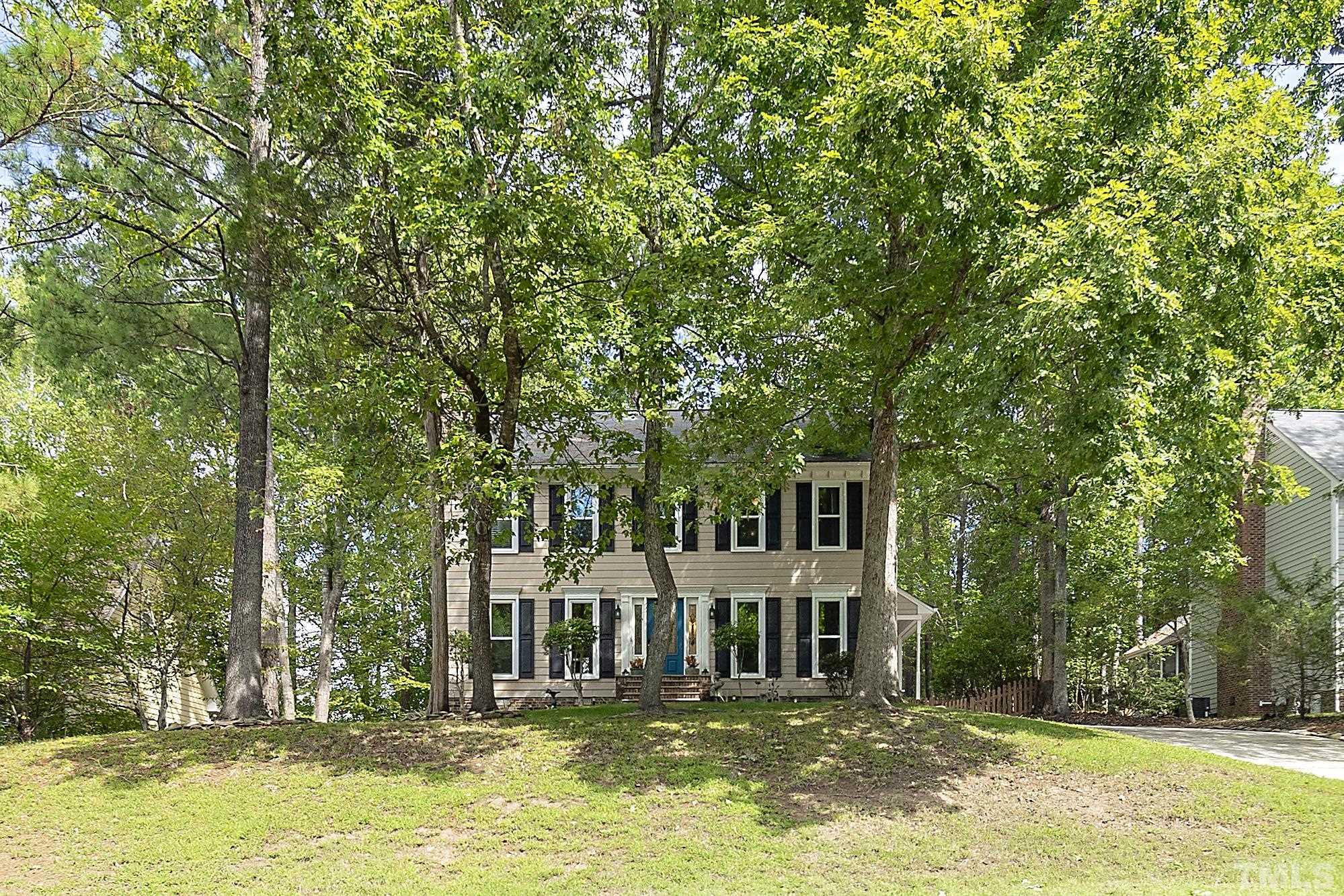 a front view of a house with a garden and tree