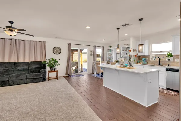 a kitchen with stainless steel appliances kitchen island granite countertop a stove a sink and a refrigerator with wooden floor