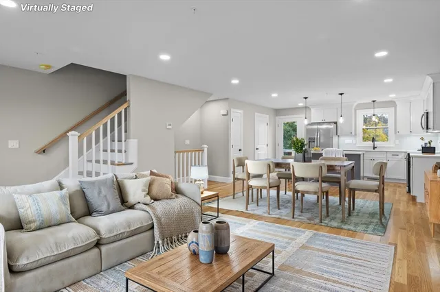 a living room with furniture kitchen view and a wooden floor