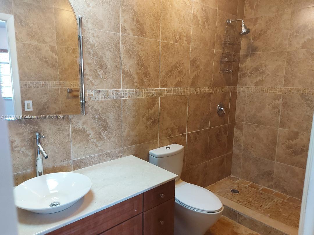 20033 Northeast 2nd Place, Unit 20033 Miami, FL 33179 - Photo 19 of 26 a bathroom with a sink a toilet and shower