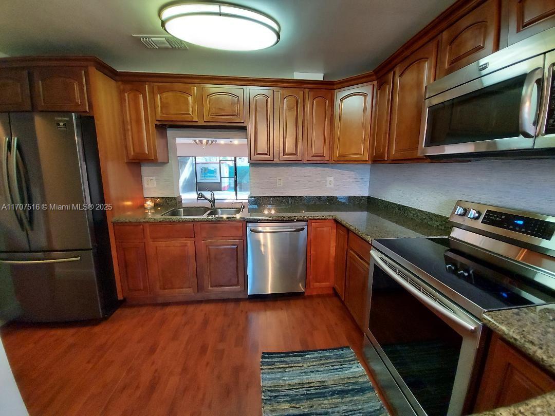 20033 Northeast 2nd Place, Unit 20033 Miami, FL 33179 - Photo 2 of 26 a kitchen with stainless steel appliances granite countertop a stove a sink dishwasher a refrigerator and a microwave