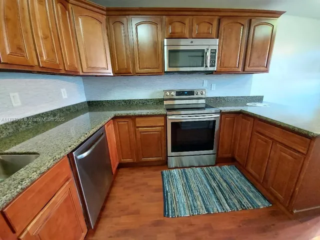 a kitchen with stainless steel appliances granite countertop a stove a sink and a microwave