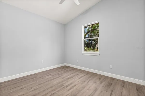 a view of an empty room with wooden floor and a window