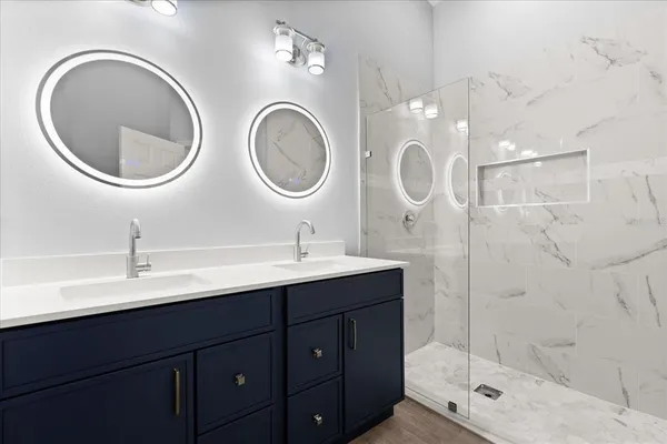 a bathroom with a double vanity sink mirror and shower