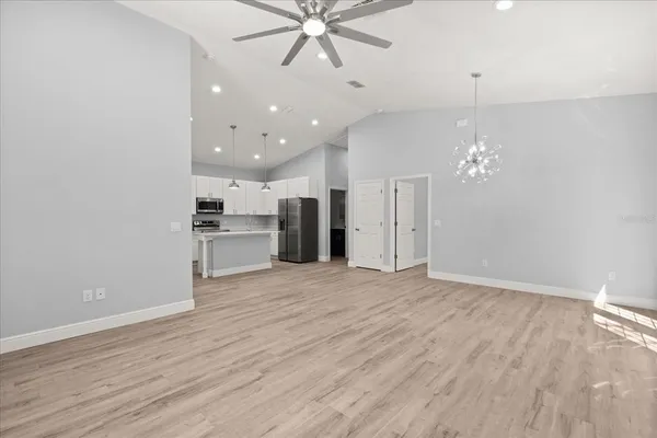 a view of an empty room with wooden floor and a kitchen