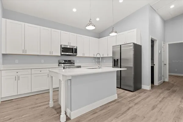 a kitchen with stainless steel appliances white cabinets and wooden floor