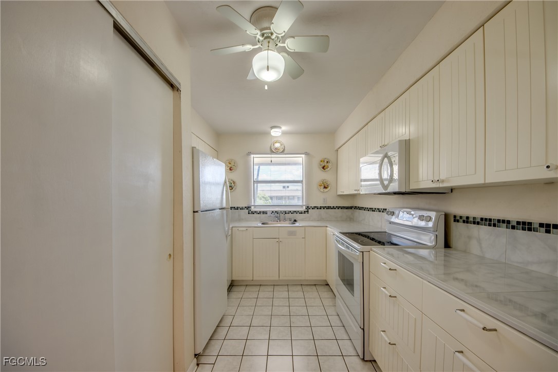 909 Southeast 46th Lane, Unit 202 Cape Coral, FL 33904 - Photo 13 of 38 a kitchen with a sink a refrigerator and cabinets