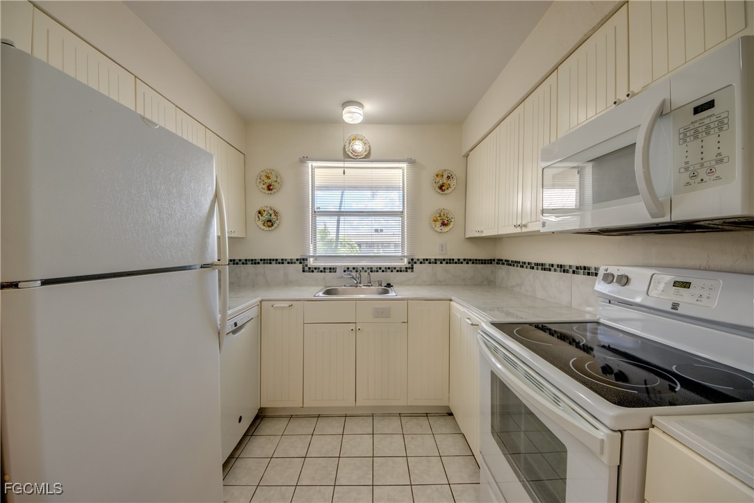 909 Southeast 46th Lane, Unit 202 Cape Coral, FL 33904 - Photo 14 of 38 a kitchen with a stove a sink and a refrigerator