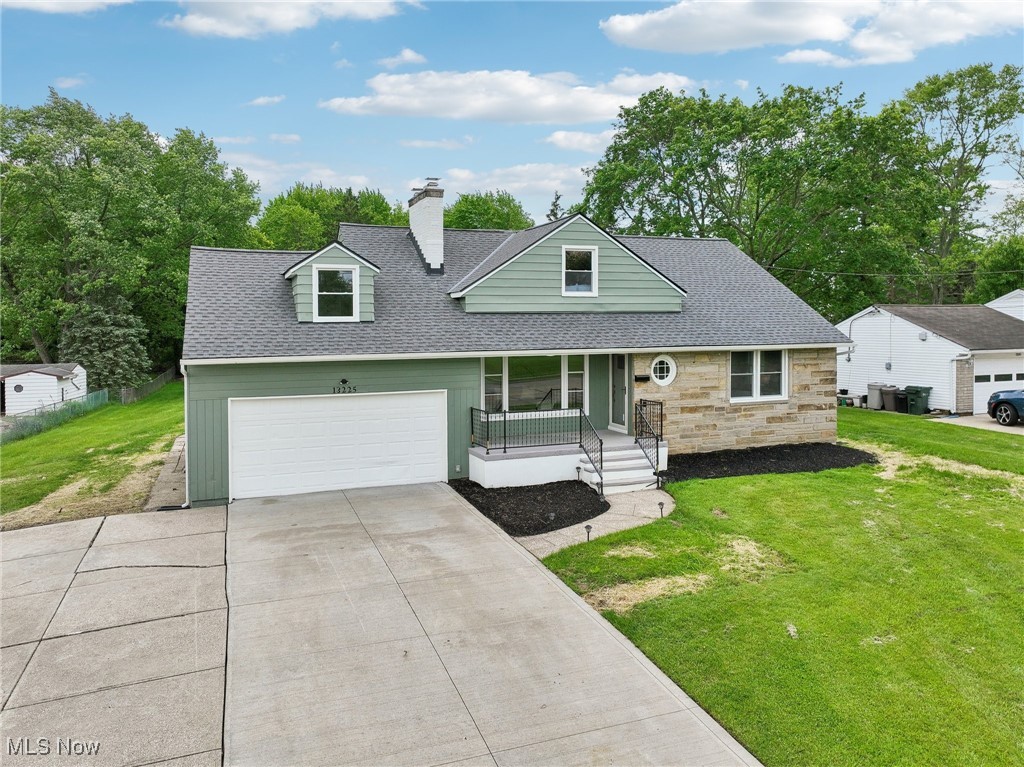 View of front of house with roof with shingles, driveway, a front yard, and a chimney