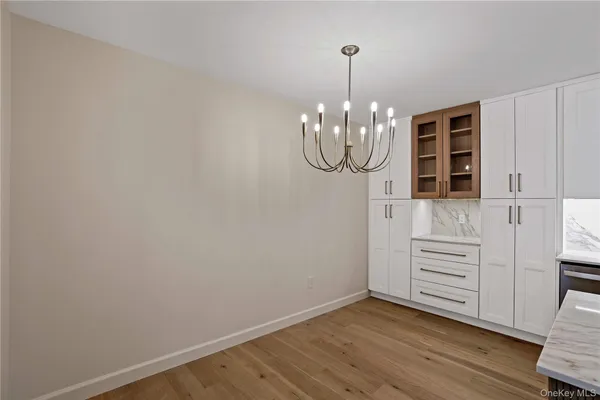 a view of a chandelier in wooden floor and cabinet in a room