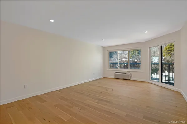 a view of an empty room with a window and wooden floor