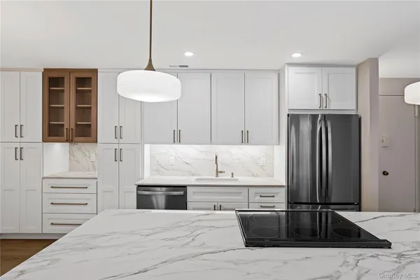 a kitchen with kitchen island granite countertop a refrigerator and a sink