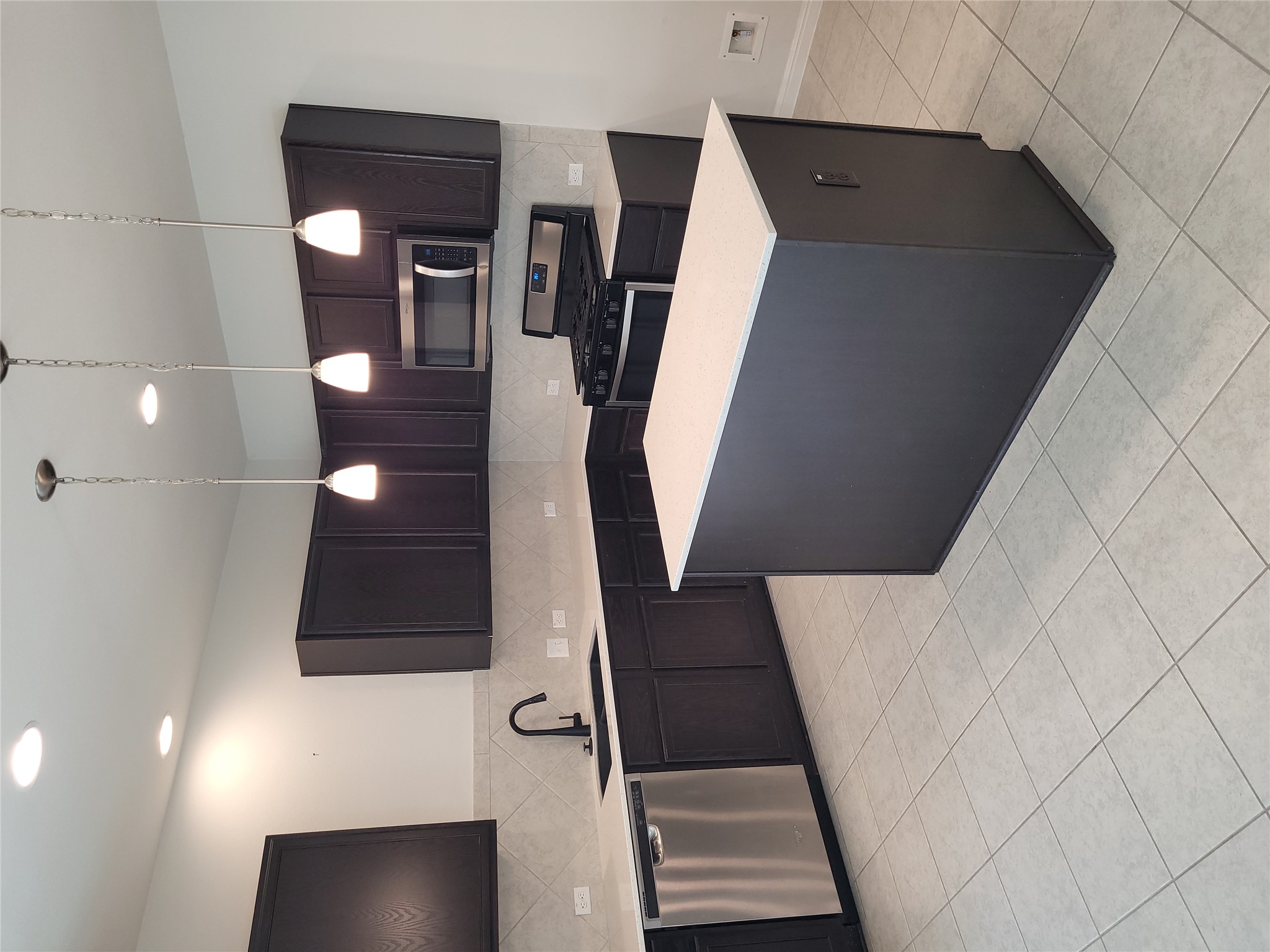 8308 Daisy Cutter Crossing Georgetown, TX 78626 - Photo 8 of 27 A contemporary kitchen features an island, ample dark cabinetry, and stainless steel appliances.