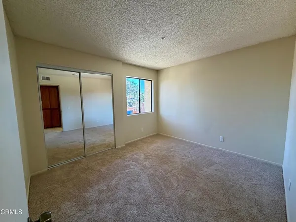 an empty room with window in back and closet area