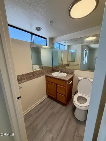a bathroom with a granite countertop toilet sink and mirror