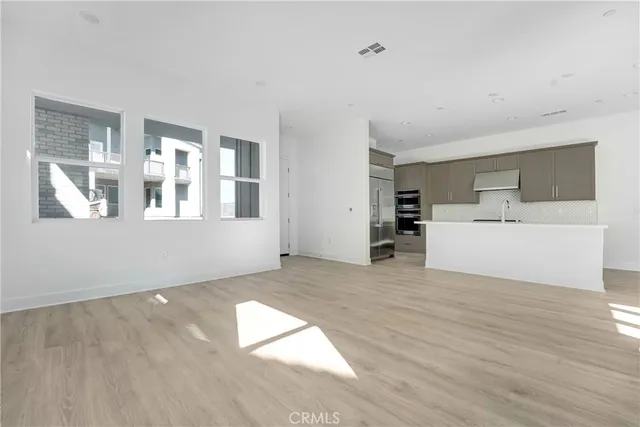 a view of a big room with wooden floor and windows
