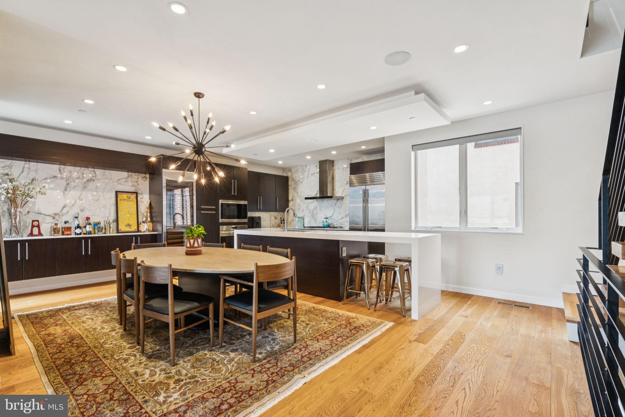 206 North 22nd Street, Unit E Philadelphia, PA 19103 - Photo 15 of 50 a large dining hall with stainless steel appliances granite countertop a stove a sink a dining table and chairs with wooden floor