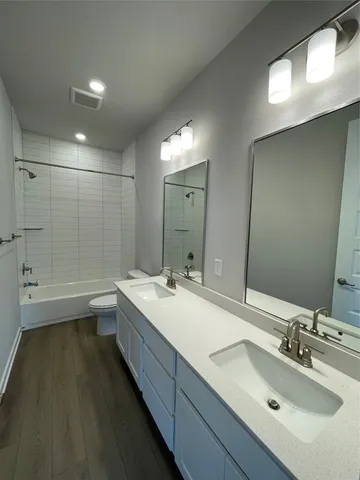 a view of an empty room with wooden floor and kitchen