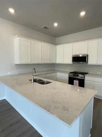 a kitchen with stainless steel appliances granite countertop a sink a window and wooden floors