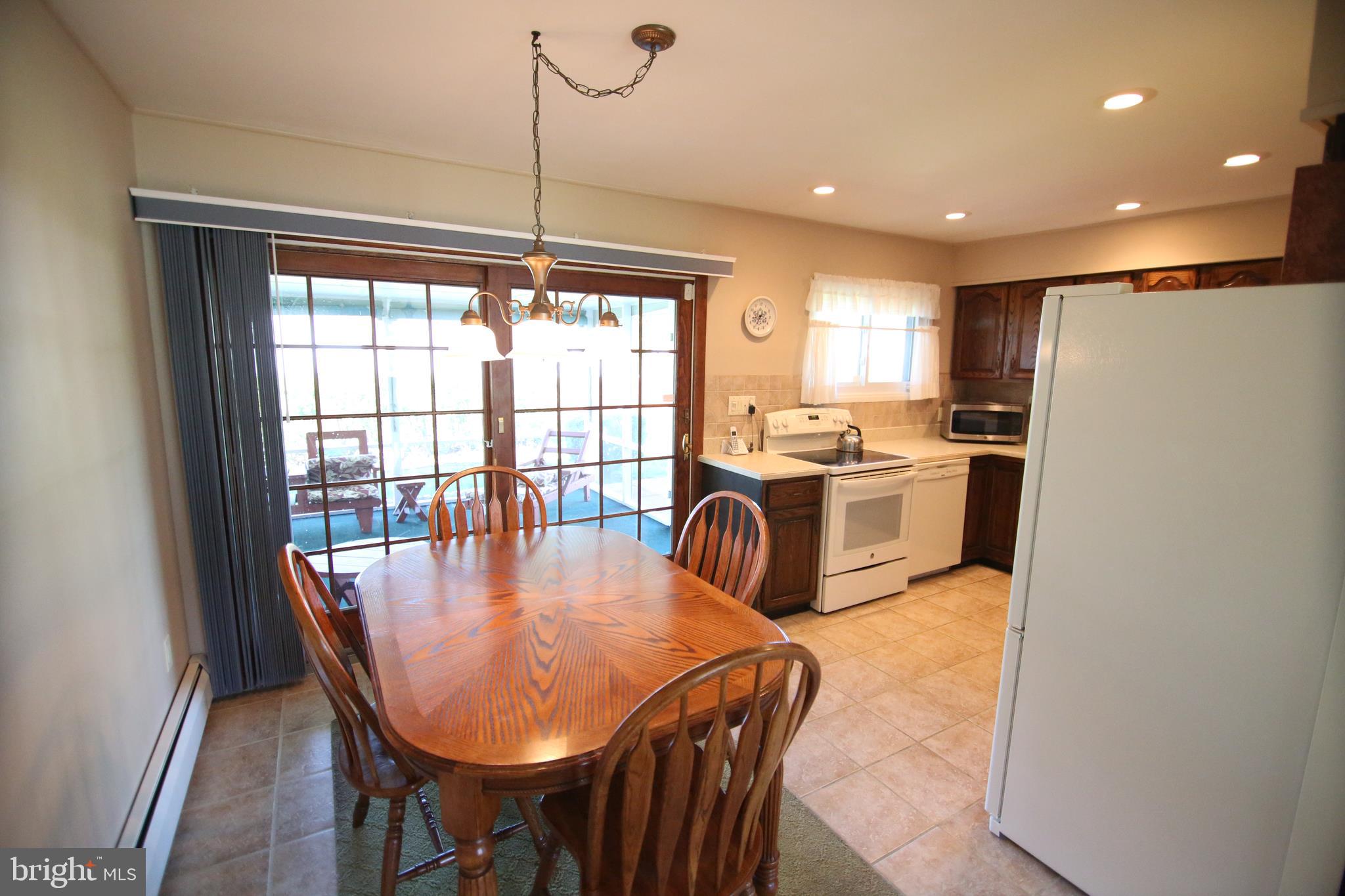 47 Trellis Road Levittown, PA 19056 - Photo 11 of 34 a kitchen with stainless steel appliances granite countertop a stove a refrigerator a sink a dining table and chairs with wooden floor
