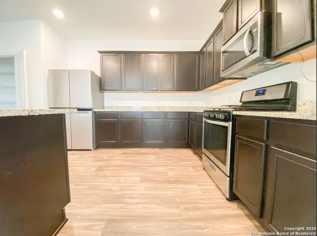 a kitchen with stainless steel appliances granite countertop a refrigerator and a stove top oven