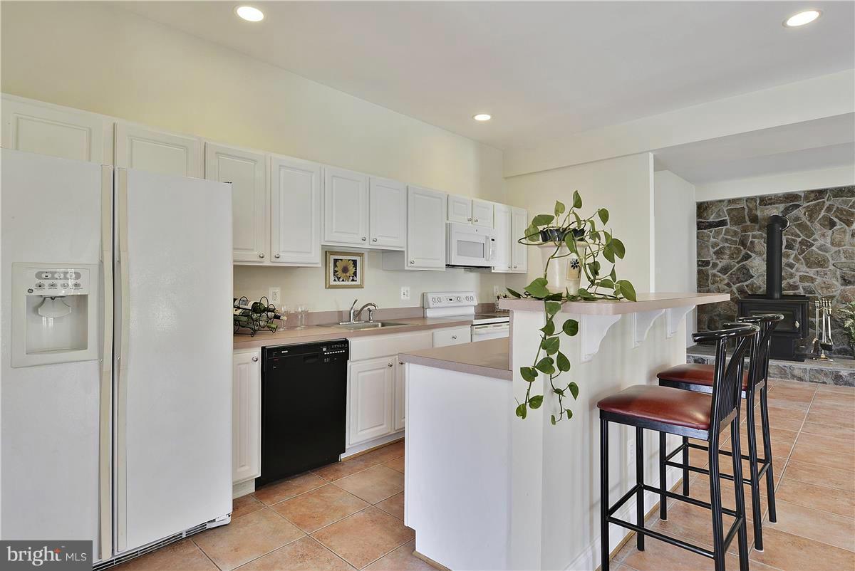 16809 Oak Hill Road Silver Spring, MD 20905 - Photo 22 of 30 a kitchen with stainless steel appliances granite countertop white cabinets a sink a stove a dining table and chairs