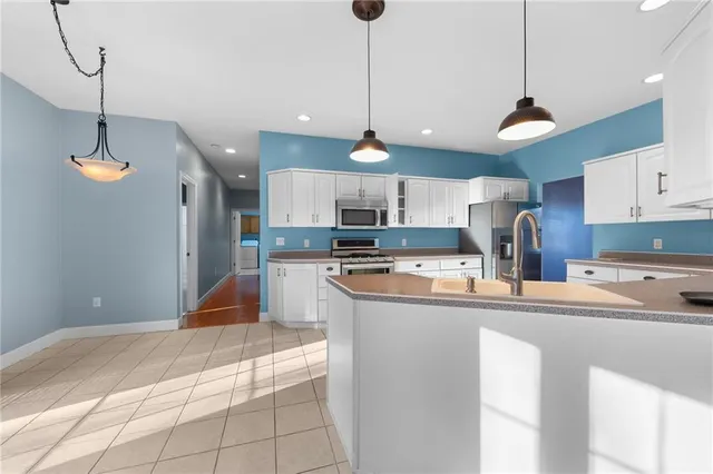 a large kitchen with stainless steel appliances granite countertop a sink a stove a refrigerator a center island and cabinets