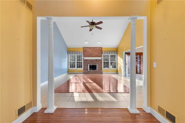 a view of a livingroom with a fireplace a ceiling fan and wooden floor