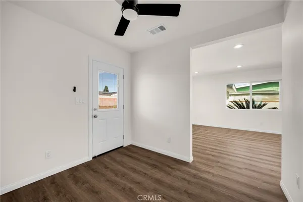 a view of an empty room with wooden floor and window