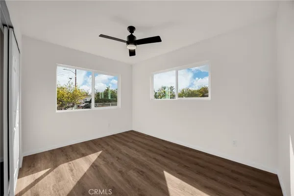a view of empty room with wooden floor and fan