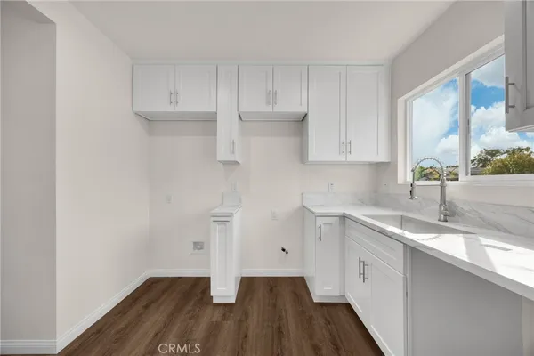 a kitchen with a sink dishwasher and cabinets with wooden floor