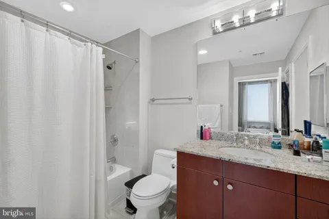 a bathroom with a granite countertop sink toilet and shower