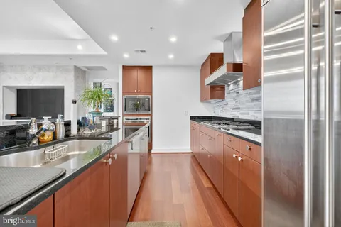 a kitchen with stainless steel appliances granite countertop a sink a stove and a wooden floors