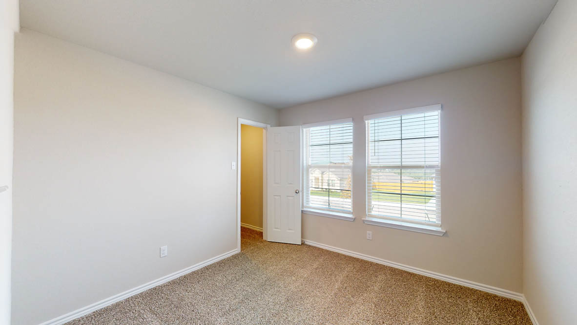429 Creekfall Road Burnet, TX 78611 - Photo 20 of 28 A well-lit bedroom with soft carpeting and dual windows overlooking the neighborhood.