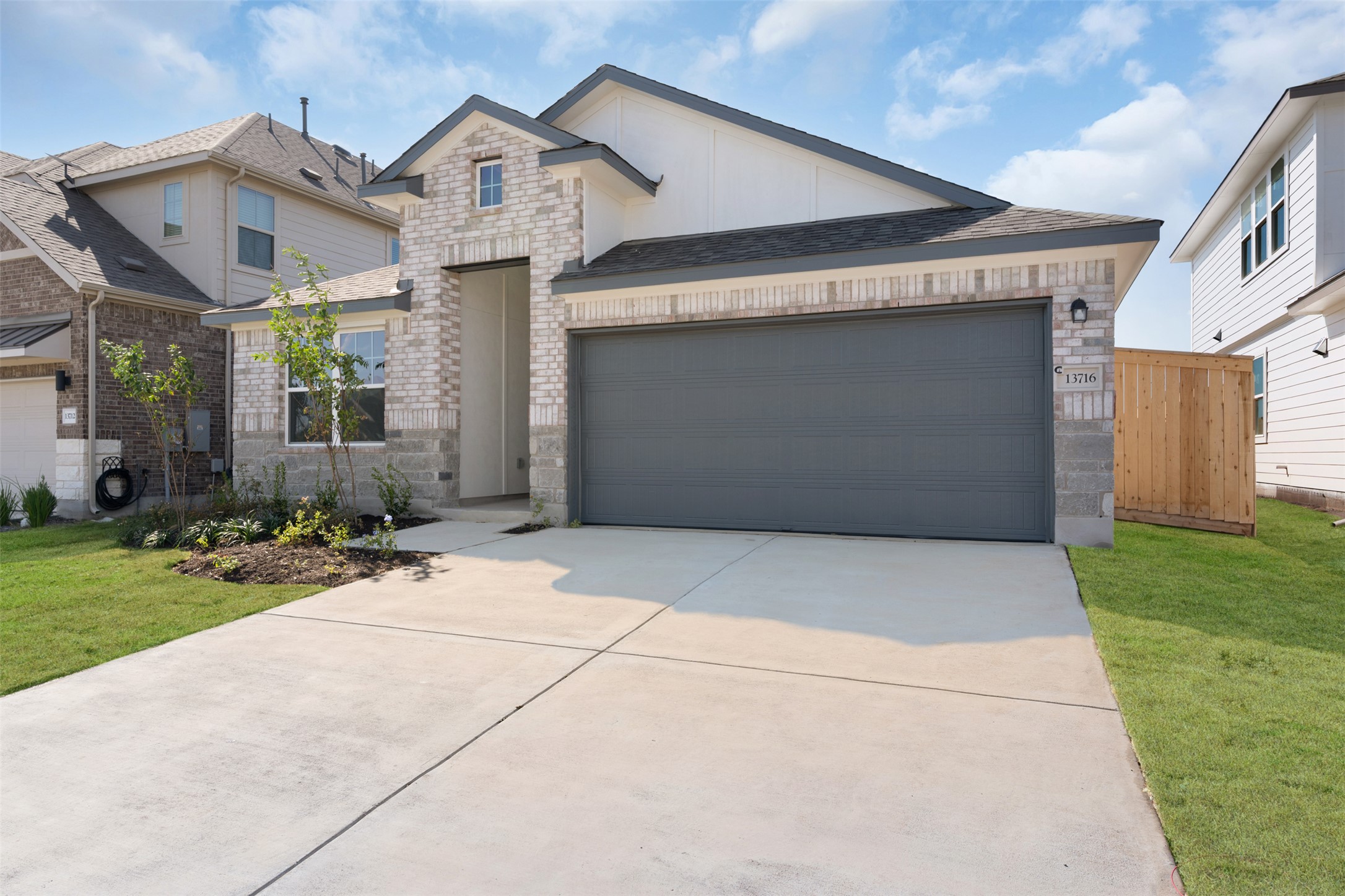 25608 Wheat Seed Lane Elgin, TX 78621 - Photo 11 of 17 View of front facade featuring a garage, brick siding, concrete driveway, board and batten siding, and a front yard