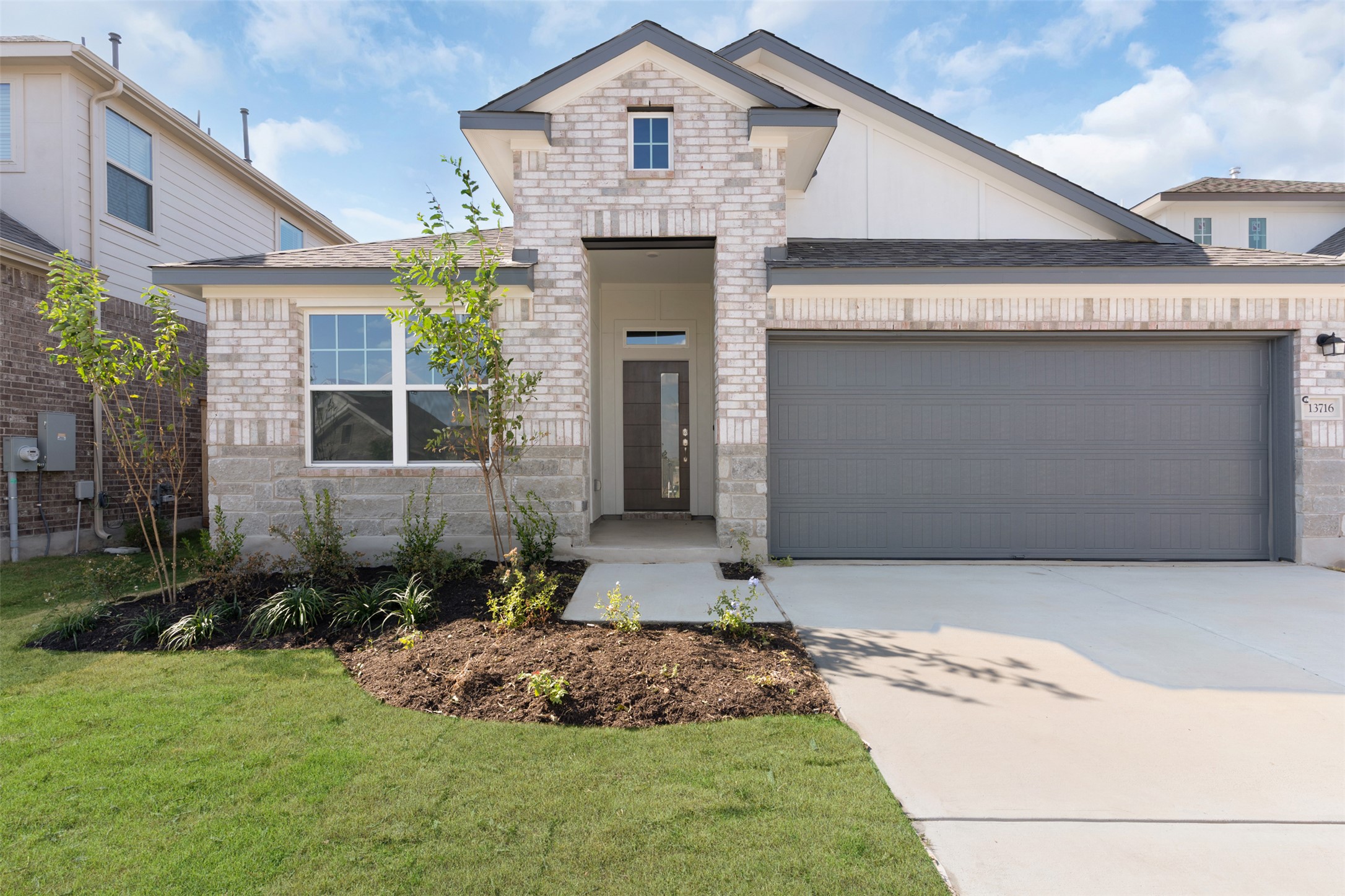25608 Wheat Seed Lane Elgin, TX 78621 - Photo 12 of 17 View of front facade featuring an attached garage, concrete driveway, brick siding, and a front yard