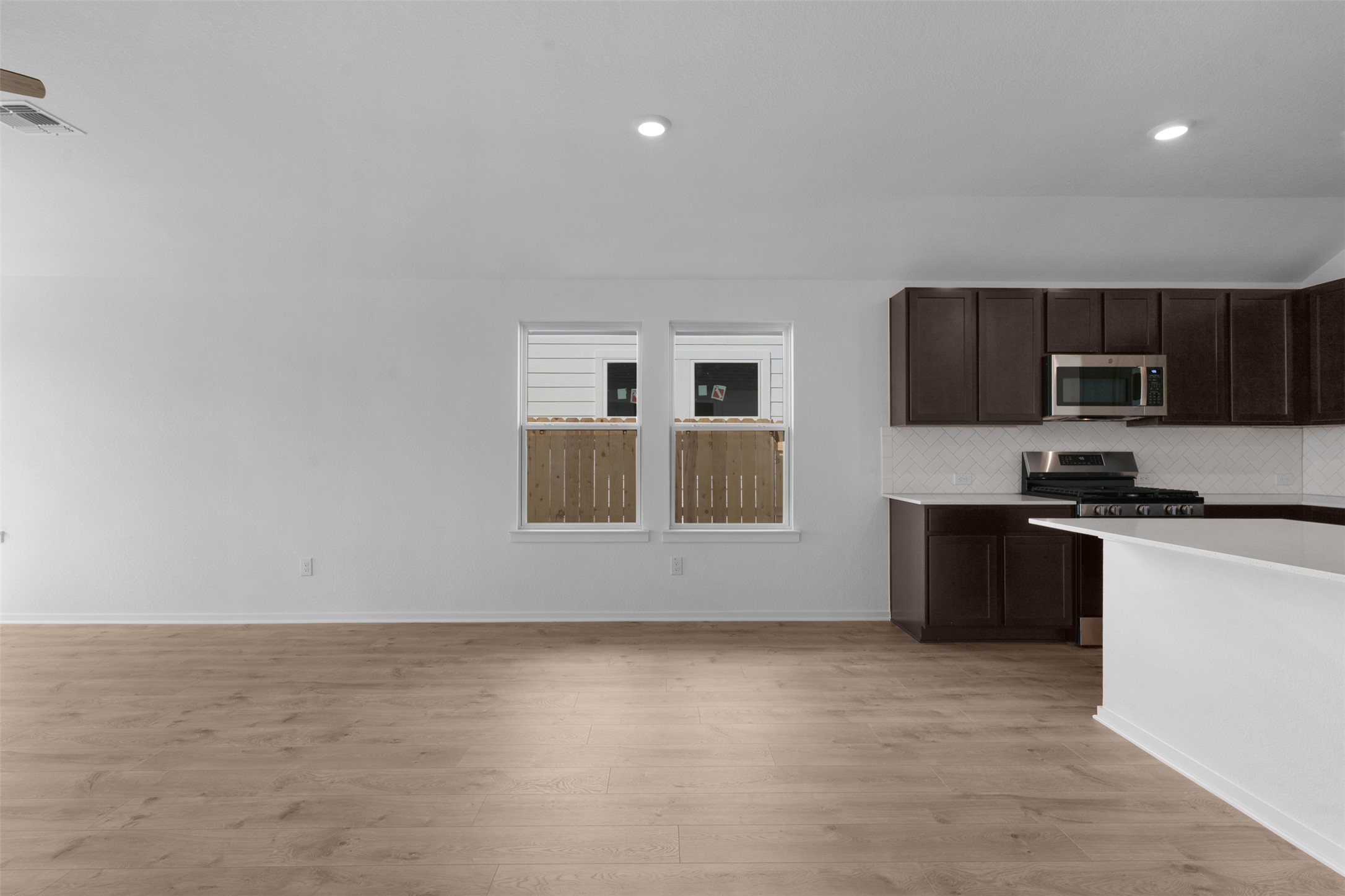 25608 Wheat Seed Lane Elgin, TX 78621 - Photo 2 of 17 Kitchen with dark wood finish cabinetry, stainless steel appliances, light wood finished floors, tasteful backsplash, and recessed lighting